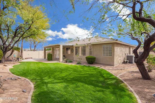 back of property with fence, a tile roof, stucco siding, a lawn, and a patio