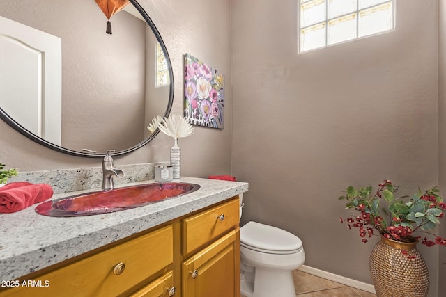 half bathroom featuring baseboards, toilet, vanity, and tile patterned flooring