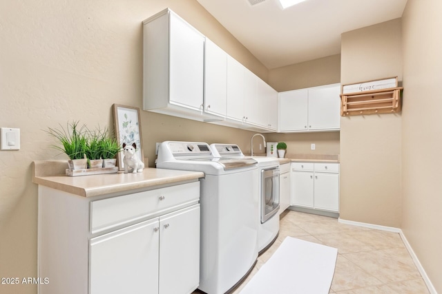 laundry room featuring light tile patterned flooring, washer and dryer, cabinet space, and baseboards