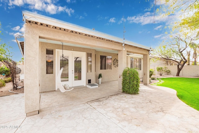 back of property with stucco siding, fence, french doors, a yard, and a patio area