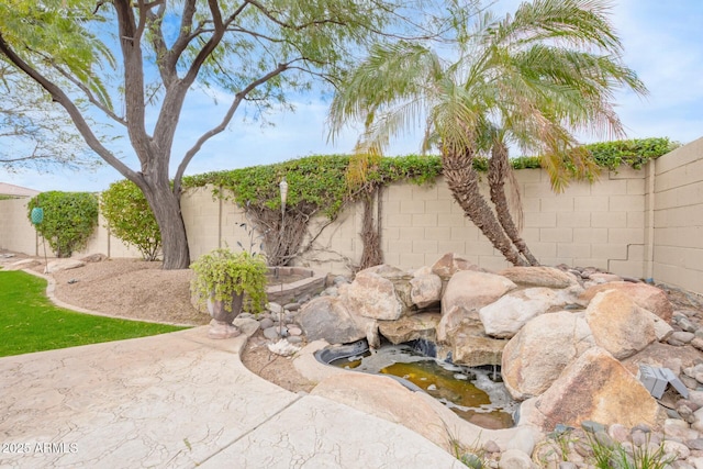 view of yard with a fenced backyard and a small pond