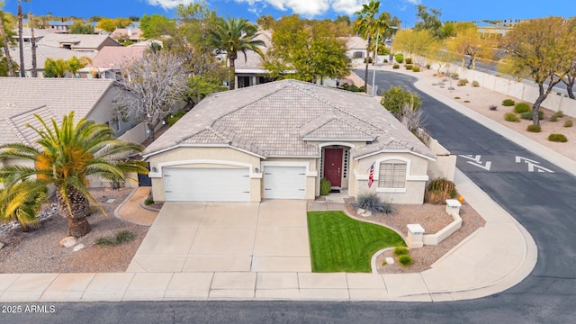 view of front facade with stucco siding, a tiled roof, an attached garage, and driveway