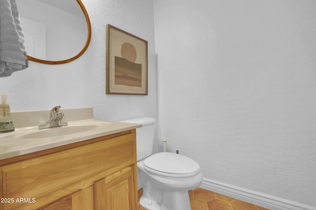 bathroom with baseboards, toilet, vanity, and tile patterned flooring