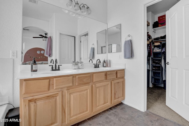 full bath with ceiling fan, double vanity, a spacious closet, and a sink