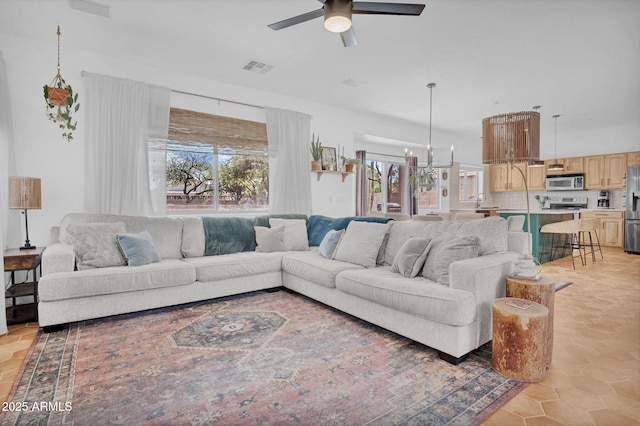 living room featuring ceiling fan with notable chandelier and visible vents