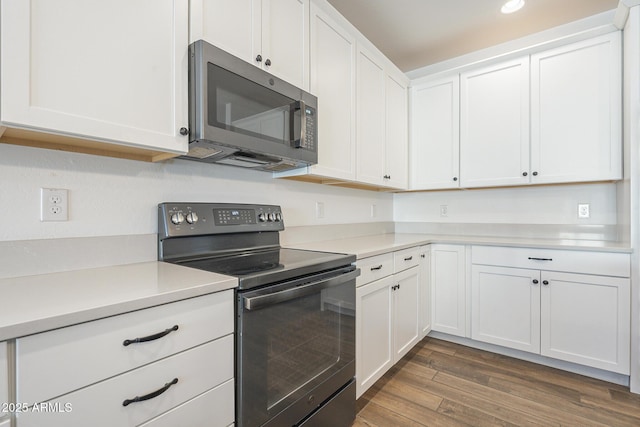 kitchen with electric range, stainless steel microwave, dark wood-type flooring, light countertops, and white cabinetry