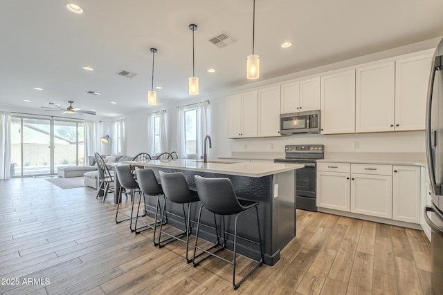 kitchen featuring a breakfast bar, light wood finished floors, stainless steel appliances, and a sink