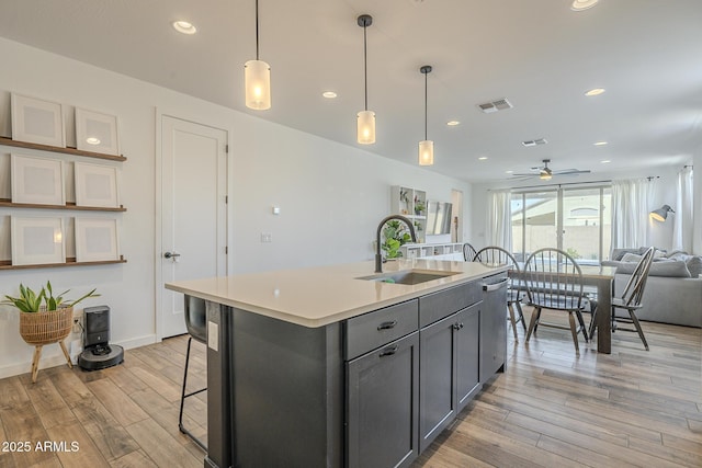 kitchen featuring gray cabinets, visible vents, light wood-style floors, open floor plan, and a sink