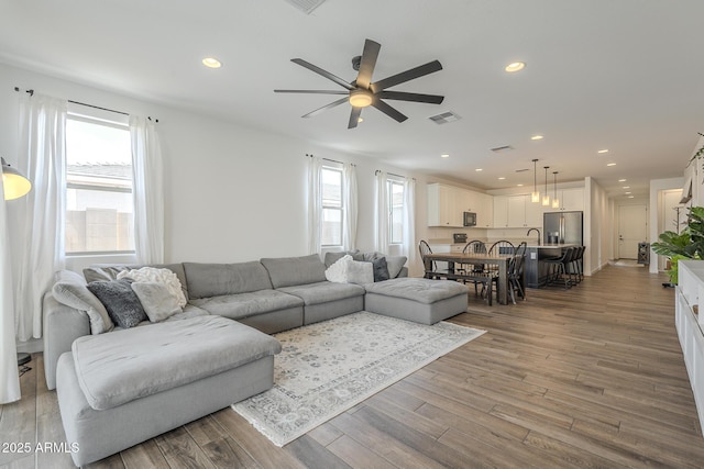 living area with recessed lighting, visible vents, ceiling fan, and wood finished floors