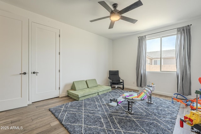 sitting room featuring ceiling fan, wood finished floors, and baseboards