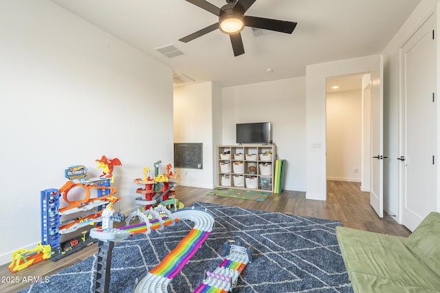 playroom with a ceiling fan, wood finished floors, visible vents, and baseboards