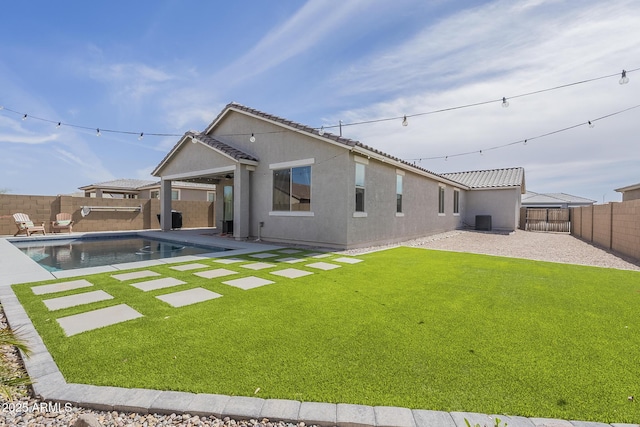 back of house featuring central AC unit, a fenced backyard, a yard, stucco siding, and a patio area