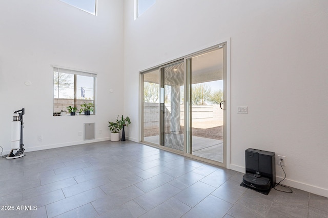 unfurnished room featuring a high ceiling and baseboards