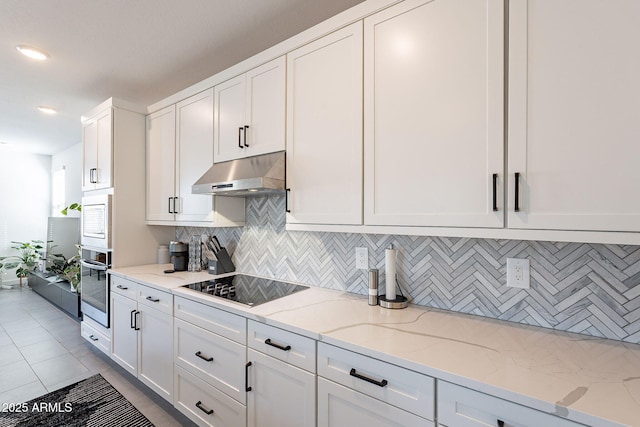 kitchen with white cabinets, light stone countertops, black electric stovetop, under cabinet range hood, and stainless steel oven