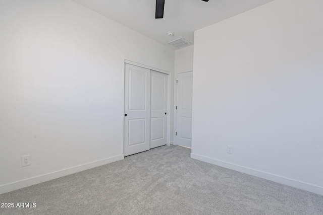 unfurnished bedroom featuring baseboards, a closet, visible vents, and light colored carpet