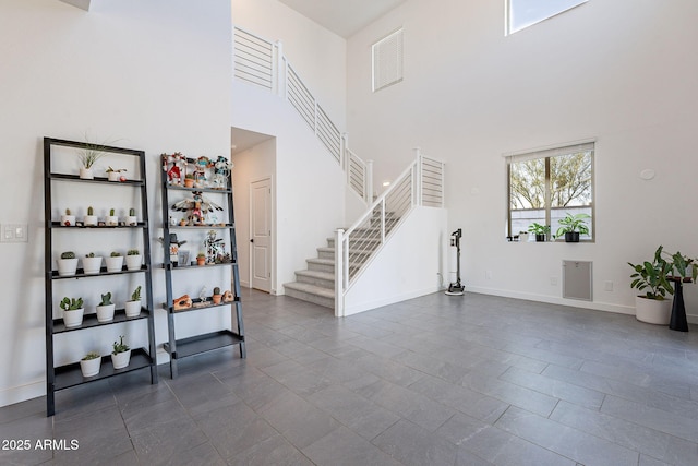 foyer with a towering ceiling, baseboards, and stairway