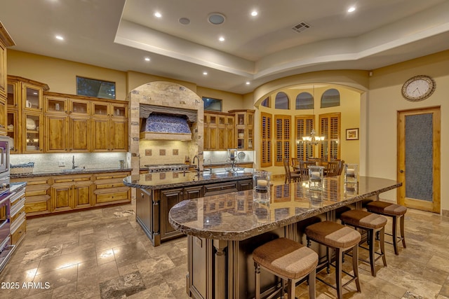 kitchen with a kitchen breakfast bar, tasteful backsplash, a spacious island, and dark stone countertops