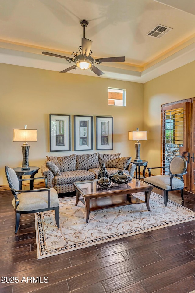 living room with dark hardwood / wood-style flooring, a raised ceiling, and a wealth of natural light