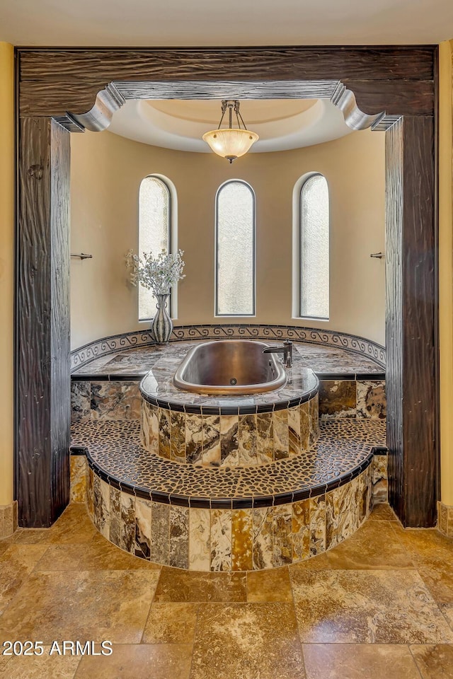 bathroom with a relaxing tiled tub and a raised ceiling