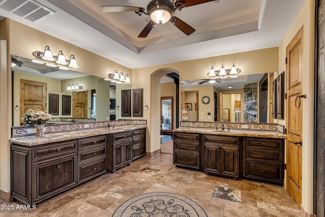 bathroom with ceiling fan, a raised ceiling, and vanity