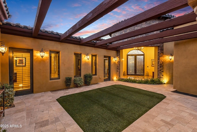 exterior entry at dusk featuring a patio area and a yard