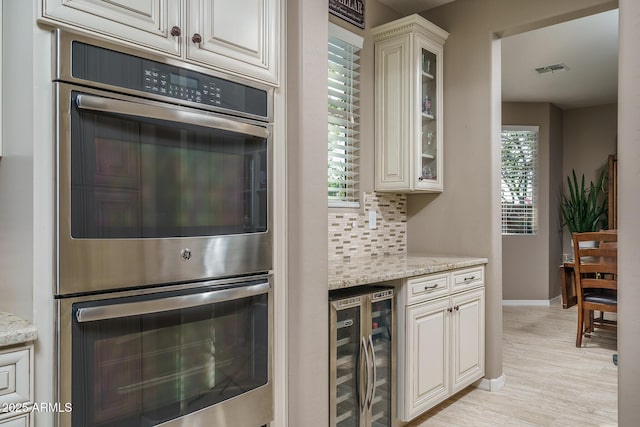 kitchen featuring wine cooler, stainless steel double oven, a wealth of natural light, and tasteful backsplash