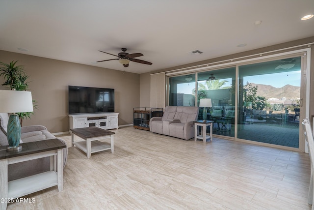 living room with baseboards, a wealth of natural light, visible vents, and a ceiling fan