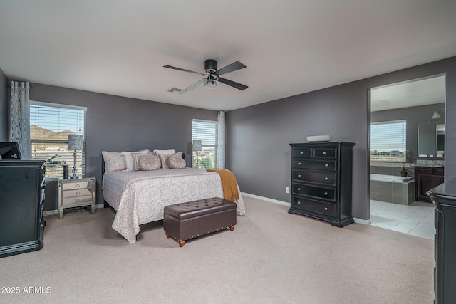 bedroom featuring visible vents, baseboards, light colored carpet, ensuite bath, and ceiling fan