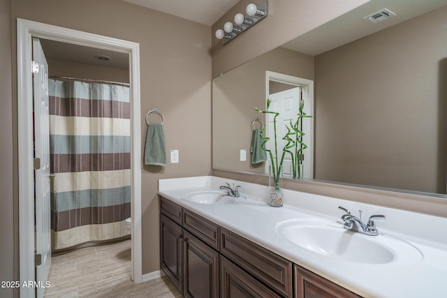 full bath featuring double vanity, visible vents, toilet, and a sink