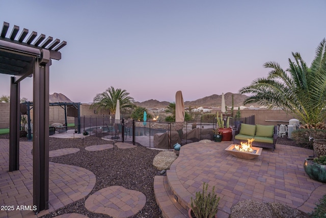 patio terrace at dusk featuring a gazebo, fence, a mountain view, a pergola, and a fire pit