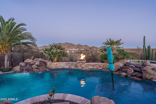 pool at dusk with a fenced backyard, a mountain view, and a fenced in pool