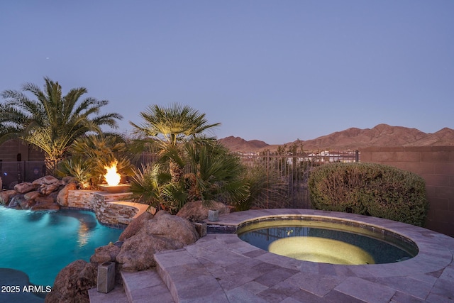 view of pool featuring a fenced in pool, a mountain view, fence, and an in ground hot tub