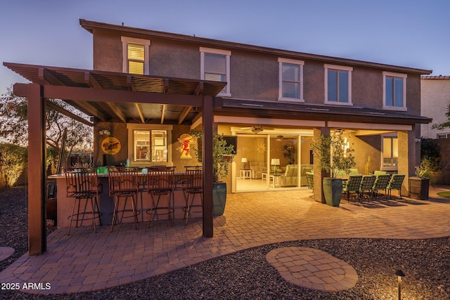 back of house with a patio, outdoor dining area, outdoor dry bar, a pergola, and stucco siding