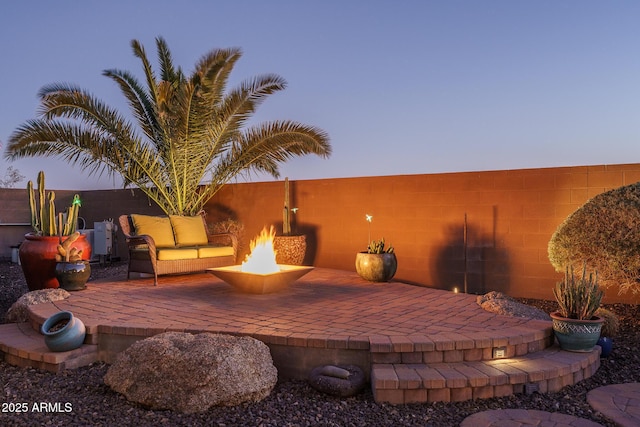 patio terrace at dusk with a fire pit and fence