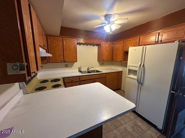 513 S Cardinal Dr, Apache Junction, AZ 85120 - kitchen with white fridge with ice dispenser, a sink, under cabinet range hood, electric range, and brown cabinetry