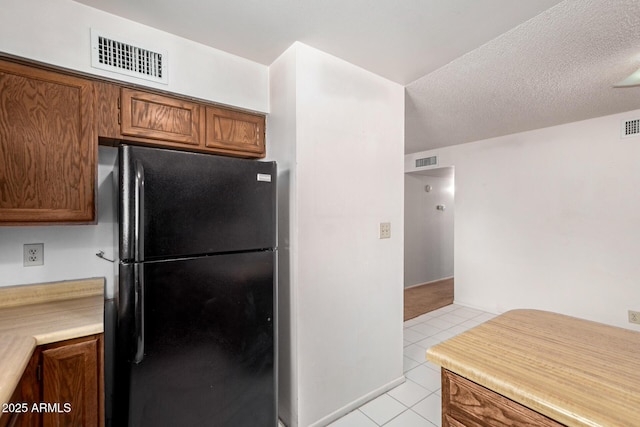 7849 E Golf Ave, Mesa, AZ 85209 - kitchen featuring freestanding refrigerator, light tile patterned flooring, brown cabinets, and light countertops