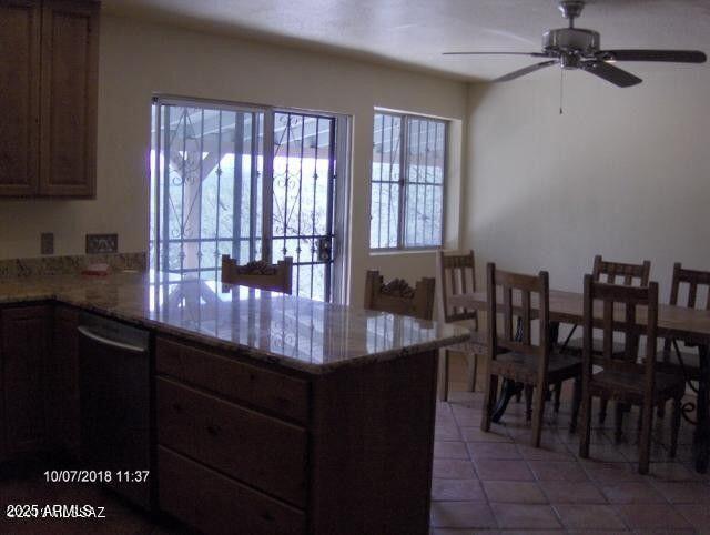 kitchen with light tile patterned flooring, ceiling fan, dishwasher, and kitchen peninsula