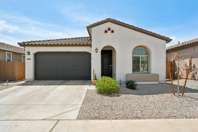 mediterranean / spanish-style house featuring stucco siding, driveway, a garage, and fence