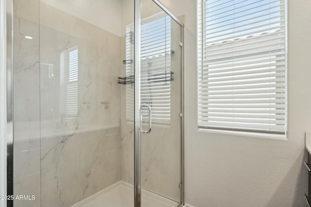full bathroom featuring a healthy amount of sunlight, vanity, and a marble finish shower