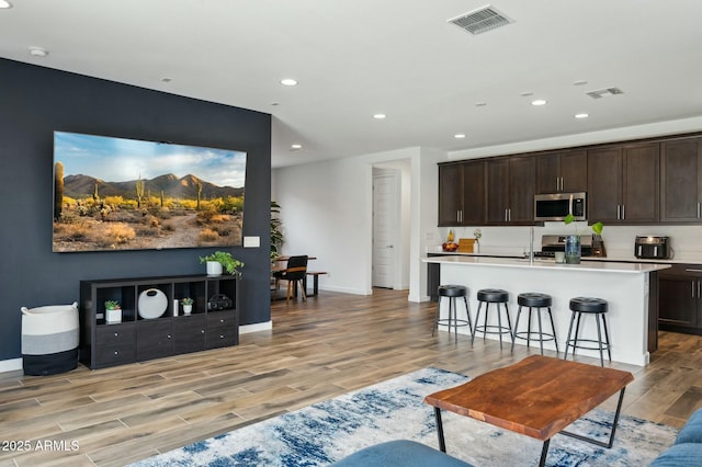 living area featuring baseboards, visible vents, light wood-style flooring, and recessed lighting