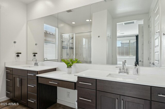 full bathroom with a shower stall, wood finished floors, a sink, and two vanities