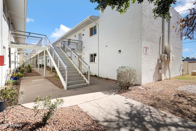 exterior space with stairway, a patio, and brick siding