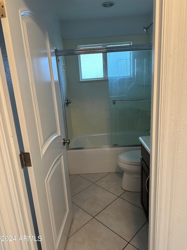 full bathroom featuring toilet, vanity, tile patterned floors, and enclosed tub / shower combo