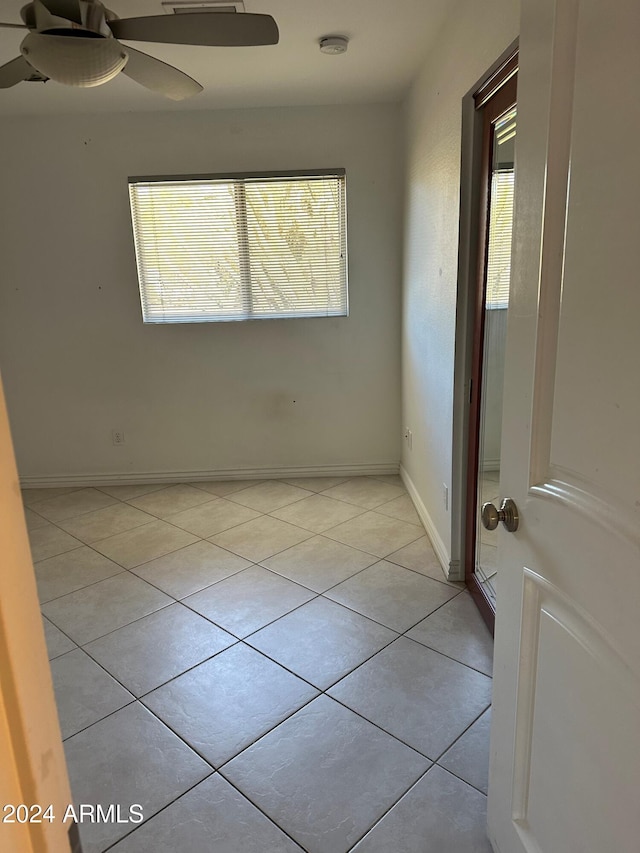 tiled spare room with a wealth of natural light and ceiling fan