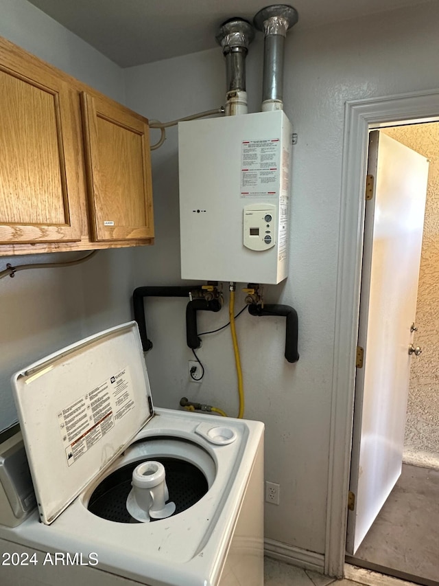 laundry room with tankless water heater, cabinets, and washer / clothes dryer