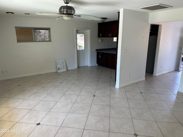 interior space featuring ceiling fan, light tile patterned flooring, and dark brown cabinetry