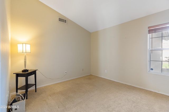 carpeted spare room with lofted ceiling