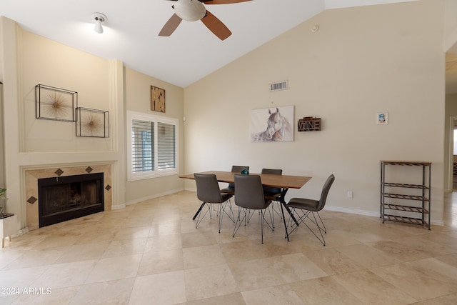 dining room with a tile fireplace, light tile patterned floors, high vaulted ceiling, and ceiling fan