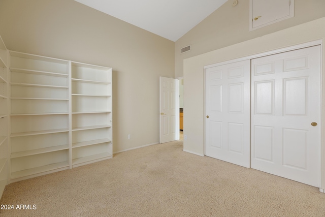 unfurnished bedroom with light carpet, a closet, and vaulted ceiling