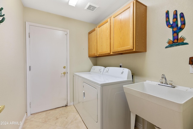 washroom featuring cabinets, light tile patterned floors, washing machine and clothes dryer, and sink